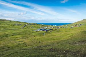 Beautiful green mountain in Skálavík, where Mølin Guesthouse in located by the sea.